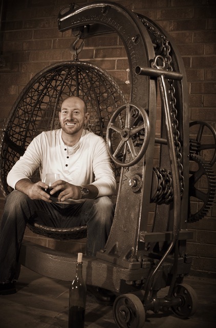 Chris-Lutzweiler, fabricant de meubles industriels, assis dans son fauteuil suspendu rustique.